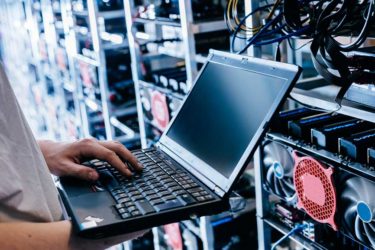 IT specialist working on computer in bitcoin and crypto currency mining farm_