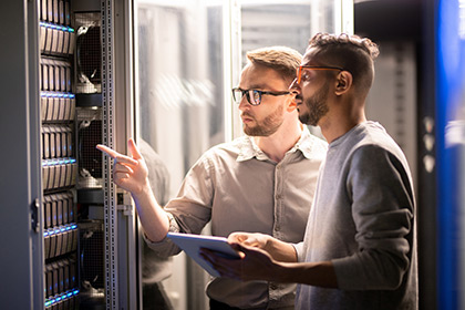 Two IT professionals examine a data center server. With IBM TLS data erasure, server erasures can be launched automatically based on policy. 